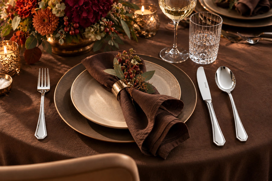 Klassisch gedeckte Herbsttafel mit Berndorf Besteck, brauner Serviette und Kerzen